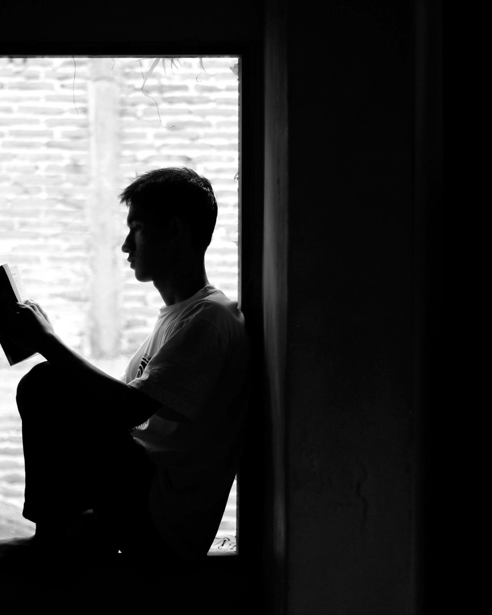 A person reading in the light of a doorway